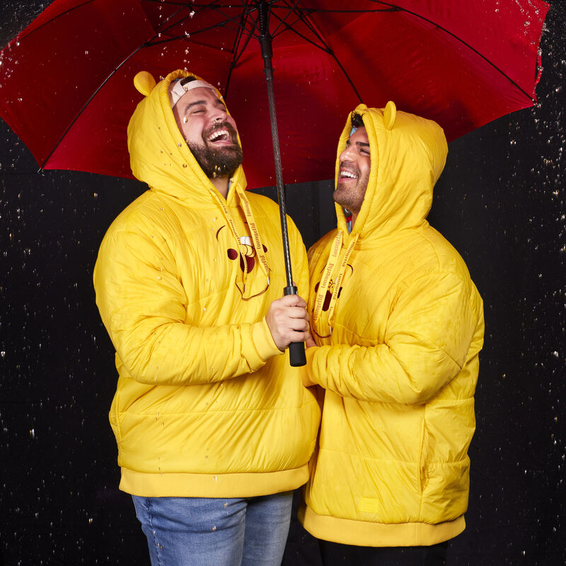 Two men wearing the Winnie the Pooh Rainy Day Cosplay Puffer Unisex Hoodie while standing under a red umbrella while it rains 